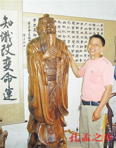 图为陈嘉敏手扶着自己雕刻完成的 2米多高的核桃原木孔子像。 图为陈嘉敏手扶着自己雕刻完成的 2米多高的核桃原木孔子像。
